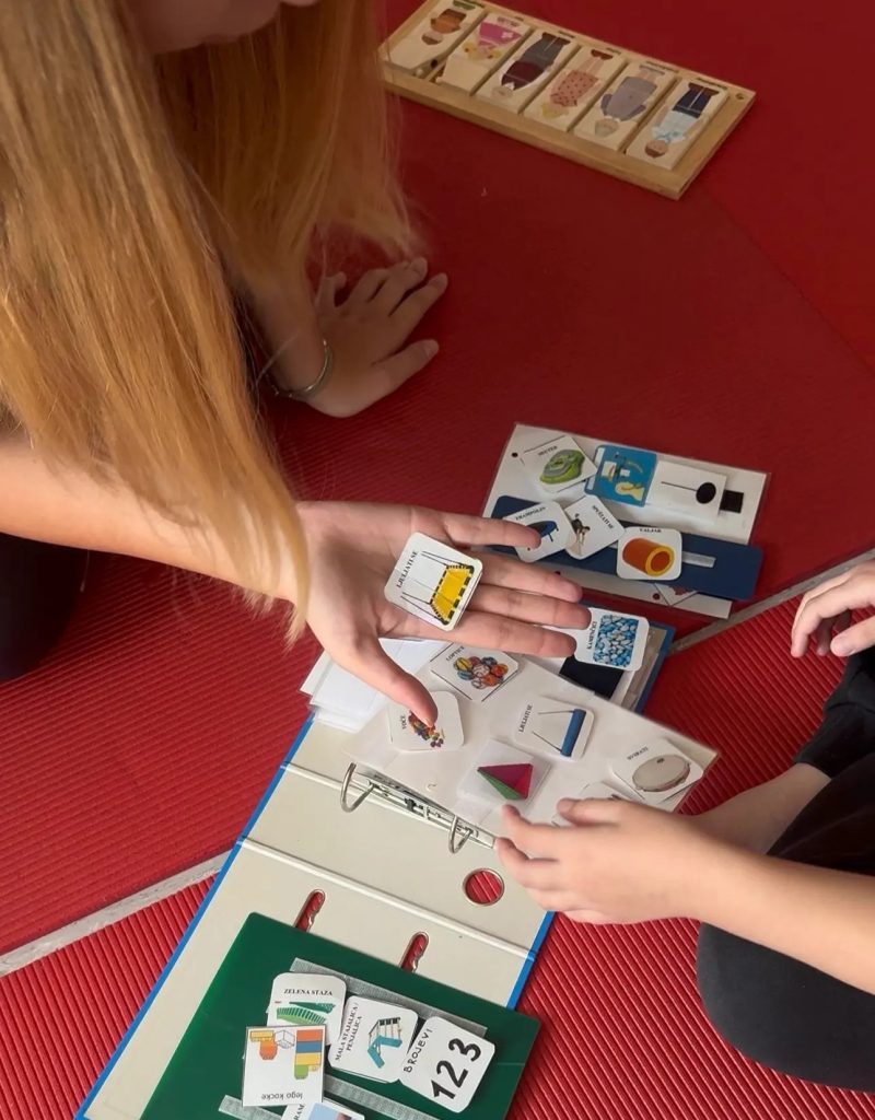 > **Child using PECS communication cards during therapy with support from a therapist.**